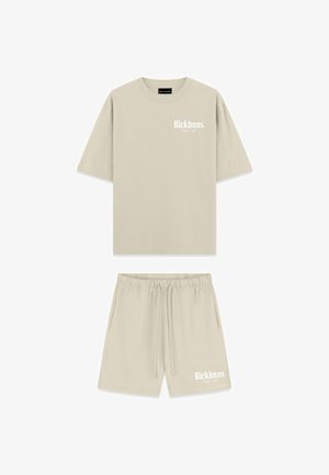Beige katoenen t-shirt en shortset met een losse pasvorm, korte mouwen, een elastische tailleband en witte logo-tekst op beide stukken.