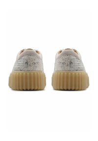 Light-colored sneakers with textured metallic upper, rounded back, and thick rubber sole featuring vertical grooves for added grip.