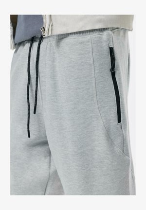 Graue Sweatpants aus einem weichen Baumwollgemisch, mit tailliertem Design, elastischem Bund mit Kordelzug und seitlichen Reißverschlusstaschen.