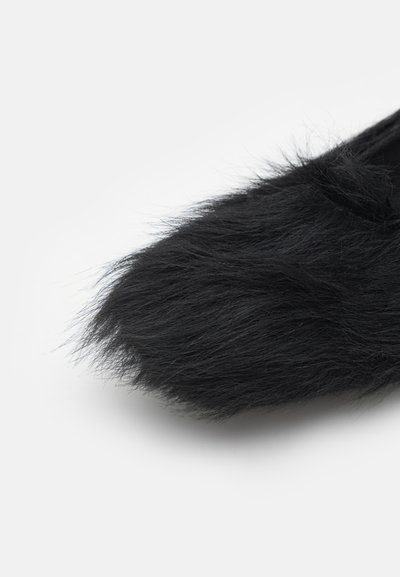 Black fur slide shoe with a soft, fluffy texture. Features a rounded toe and seamless design for a sleek appearance.