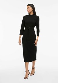 Black midi dress made of soft fabric, featuring a high neckline, three-quarter sleeves, and a fitted waist with a matching belt.