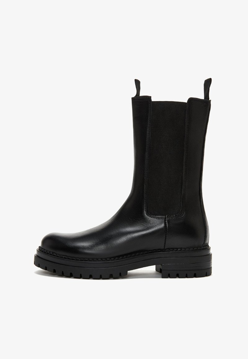 Botas negras hasta el tobillo con un upper de cuero suave, paneles laterales elásticos y una suela de goma gruesa con profundas bandas de rodadura para mayor tracción.