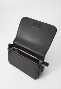 Borsa a tracolla in pelle nera con un scomparto con zip e texture liscia. La chiusura a patta rivela un interno di colore chiaro.