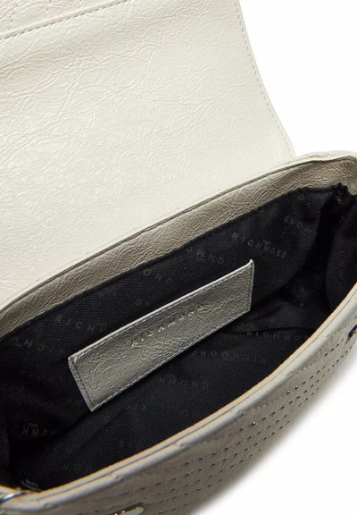 Interno della borsa in pelle grigia perforata con fodera bianca; presenta una base in tessuto nera con etichetta del logo e una pattina di chiusura liscia.