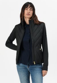 Gequilted zwarte jas met hoge kraag, ritsluiting en zijzakken. Duurzaam stof met een gestructureerd patroon en gouden hardware accenten.