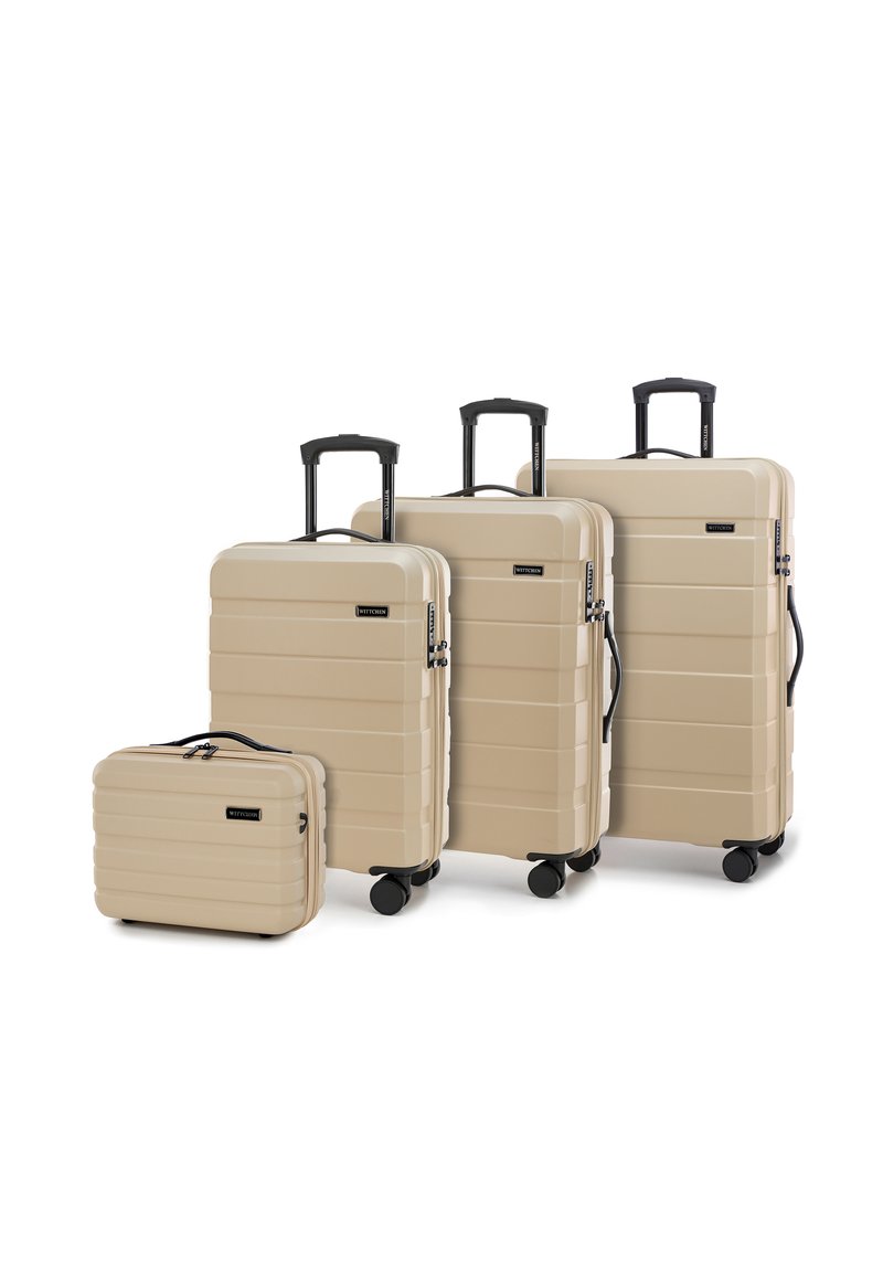 Quattro valigie rigide beige con scanalature orizzontali, maniglie nere e ruote multidirezionali. Le dimensioni variano da piccole a grandi.