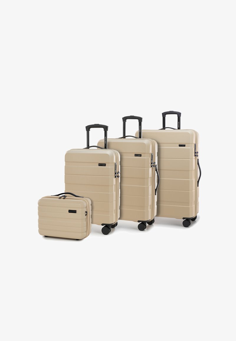 Quattro valigie rigide beige con scanalature orizzontali, maniglie nere e ruote multidirezionali. Le dimensioni variano da piccole a grandi.