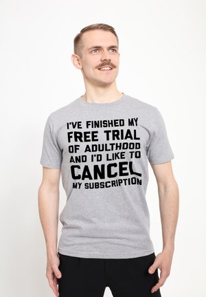 Szary T-shirt z krótkim rękawem z wyraźnym czarnym napisem: "ZAKOŃCZYŁEM MÓJ BEZPŁATNY OKRES PRÓBNY W DOROSŁOŚCI I CHCIAŁBYM ANULOWAĆ MOJĄ SUBSKRYPCJĘ."