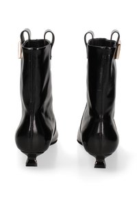 Bottines en cuir noir avec une finition brillante, bouts pointus et petits talons carrés. Elles disposent d'un tirant et d'accents de design minimalistes.