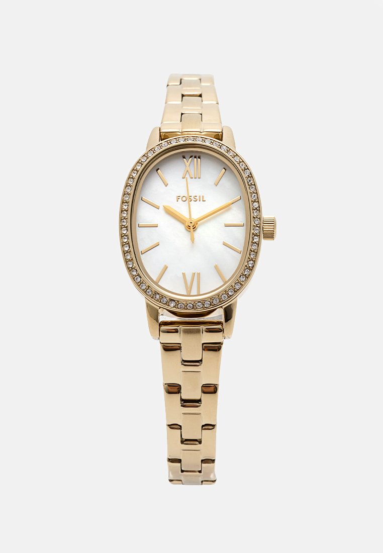 Montre Fossil dorée avec un boîtier ovale, un cadran en nacre blanche, des chiffres romains dorés et des embellissements en cristal sur la lunette et le bracelet.