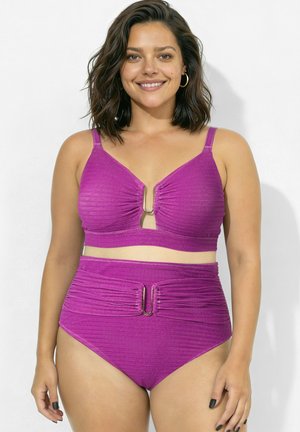 Femme souriante aux cheveux mi-longs porte un bikini violet scintillant taille haute avec des anneaux métalliques en haut et en bas.