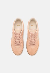 Paire de baskets en daim pêche avec lacets, panneaux latéraux beige et logo "BOSS" doré sur la languette, les côtés et les semelles intérieures, vues de dessus.