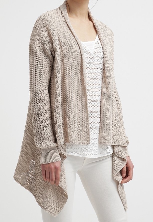 Beige Cardigan mit offenem Vorderteil, strukturierter Strickmuster, kurz geschnittenem Design und langen Ärmeln. Mehrlagiger, drapierter Saum. Über einem weißen Top getragen.