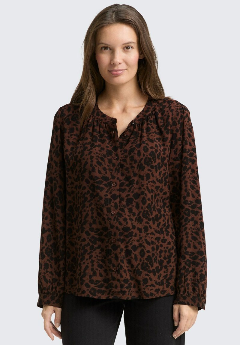 Blouse imprimé léopard marron et noir avec manches longues, encolure froncée et boutonnage sur le devant. Tissu doux avec une coupe décontractée.
