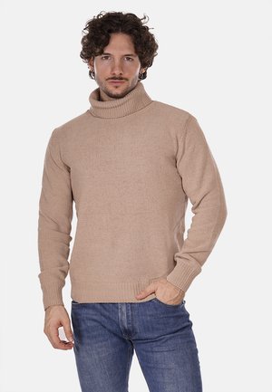 Maglione a collo alto beige con colletto e polsini a coste, realizzato in tessuto knit testurizzato, abbinato a jeans di denim blu.