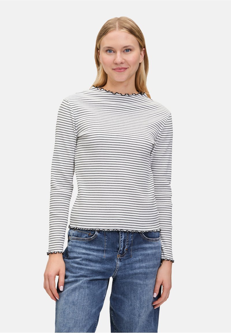Maglia a manica lunga a righe in bianco e nero, con un collo e un orlo scallop. Realizzata in materiale a coste. Abbinata a jeans in denim blu.