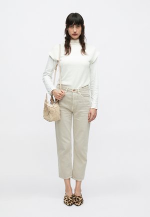 Haut blanc ajusté avec des manches courtes structurées, pantalon taille haute beige clair, sac à main matelassé beige, et ballerines imprimé léopard.