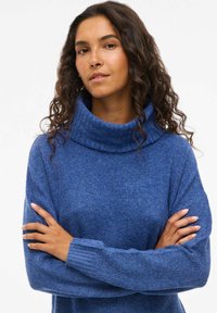 Blå turtlenecktröja i texturerad stickad tyg. Har en bred, vikbar krage och ribbade manschetter. Långa ärmar och avslappnad passform.