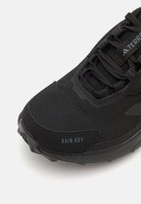 Czarny but sportowy z teksturowaną cholewką, siateczkowymi panelami, gumową podeszwą i nadrukowanym detalem "RAIN.RDY" z boku.