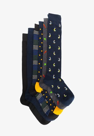 Set von acht Socken in verschiedenen Designs. Merkmale sind einfarbige Farben, Streifen, Polka-Dots und verspielte Stickereien von Enten und Paprika.