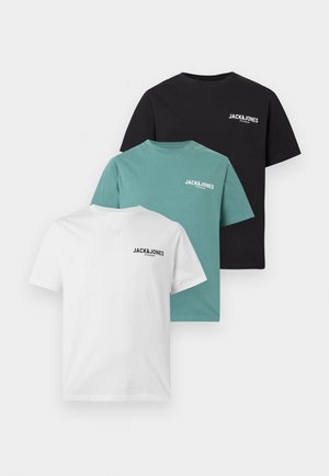 Ung mand står iført en hvid Jack&Jones t-shirt, lyseblå denimshorts, hvide sokker og sorte sneakers med hvide striber.