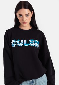 Czarny, oversize sweter z kolorowym nadrukiem tekstu "CULOR" w niebieskim i białym kolorze, o pluszowej teksturze i prążkowanym dekolcie.