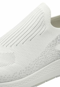 White slip-on sneaker with a textured, knitted upper featuring vertical ribbing, a patterned side, and a lightweight rubber sole.