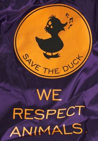 Lila Stoff mit einer schwarzen Entensilhouette in einem orangefarbenen Kreis, mit dem Text „SAVE THE DUCK“ und „WE RESPECT ANIMALS“ in orangefarbener Schrift.