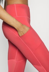 Leggings taille haute, ajustés, en rose vif, dotés d'une poche latérale et d'un design à panneaux contrastés, avec un tissu lisse et extensible.