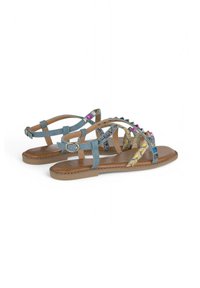 Blauwe stoffen sandalen met veelkleurige geometrische patronen en spikes. Lichtbruine zolen met decoratieve stiksels langs de randen.