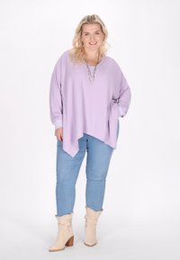 Lavendel tekstureret oversized top med lange ærmer, parret med lyseblå jeans og beige ankelstøvler med blokhæle.