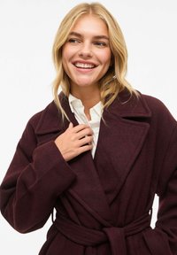 Burgundy wool wrap coat with a wide collar, belted waist, and long sleeves, featuring a textured fabric and deep color.