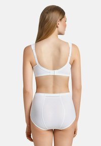 Witte naadloze beha en hooggekruiste slipjes. Verstelbare bandjes, gladde textuur en een eenvoudig ontwerp zonder zichtbare naden of patronen.