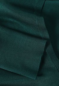 Tissu en maille vert foncé, texture lisse avec un motif côtelé. Présente des bords pliés et un aspect superposé, adapté aux vêtements.