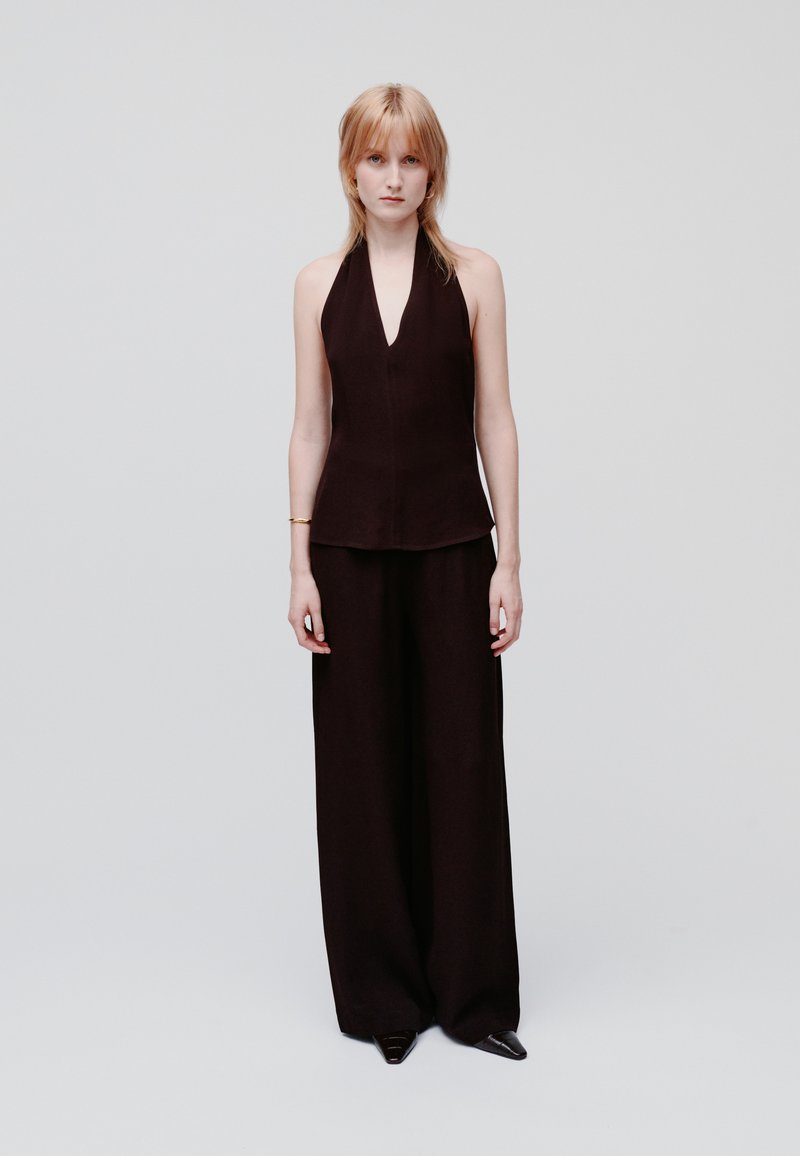 Top nero a collare alto e pantaloni palazzo realizzati in tessuto leggero. Design semplice con scollo a V, texture liscia e senza motivi o accenti visibili.