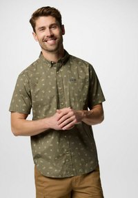 Camicia corta verde oliva con bottoni, decorata con un motivo floreale e cactus, dotata di taschino sul petto e di un logo del marchio in alto a sinistra.