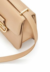 Beżowa skórzana torebka z złotym zapięciem, o strukturalnym kształcie, ze szwami na krawędziach oraz odpinanym paskiem na ramię. Gładka struktura.