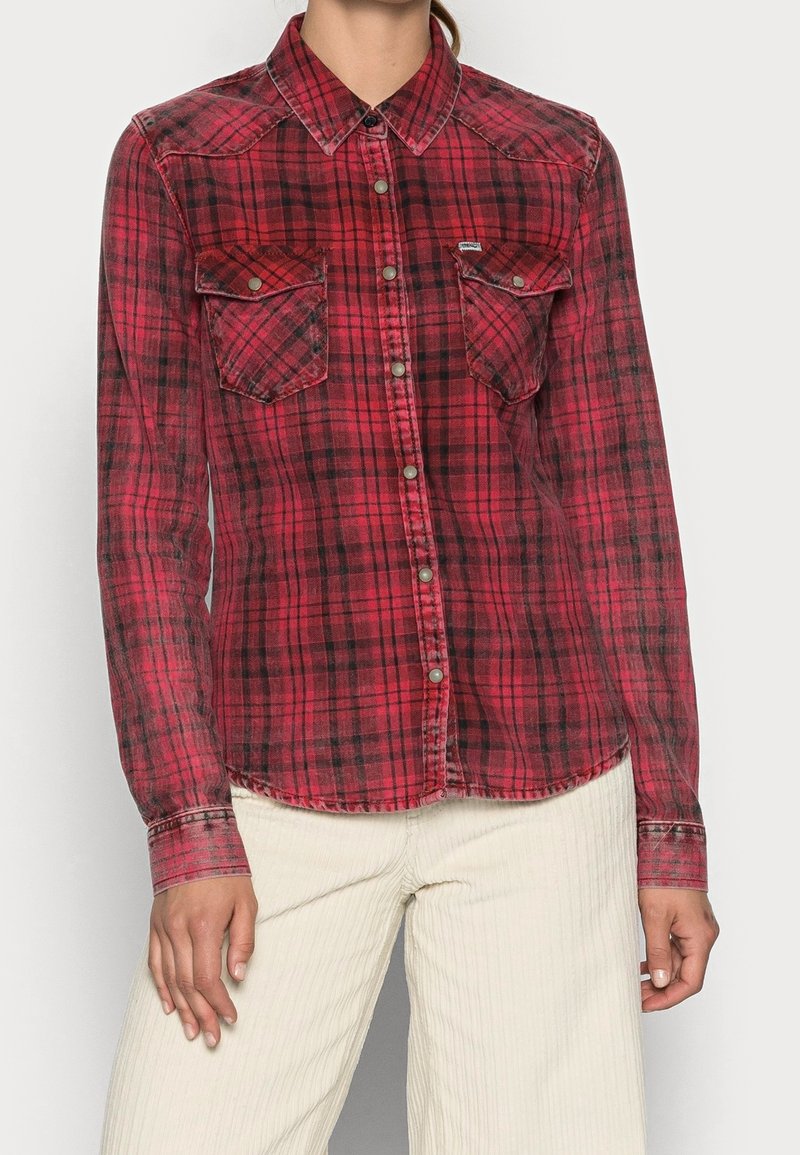 Camisa de cuadros roja y negra con mangas largas, dos bolsillos en el pecho, cierre de botones y dobladillo curvado. Hecha de un tejido suave y ligero.