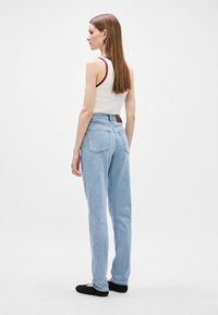 Ανοιχτό μπλε ψηλόμεσα τζιν με ίσια γραμμή, που διαθέτουν μια στάμπα στο πίσω μέρος, πέντε τσέπες και απαλή υφή από τζιν.