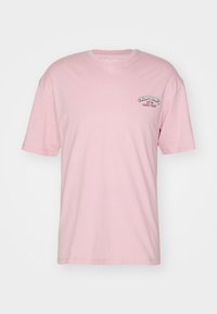 Lyserød kortærmet t-shirt lavet af bomuld. Har et lille sort grafisk tekstlogo på venstre brystområde. Normal pasform med rund halsudskæring.
