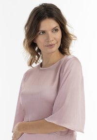 Helles rosa Blusenshirt mit kurzen, lockeren Ärmeln, strukturiertem Stoff und einem runden Ausschnitt. Glatte, dezente Oberflächenstruktur und lässige Passform.