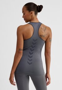 Grå racerback linne med en texturerad finish och chevronmönster på baksidan. Figursydd design, minimala sömmar och ribbad nederkant.
