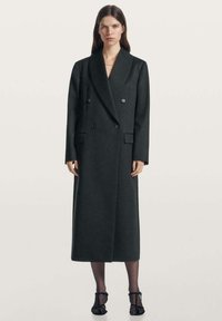 Dvouradý tmavě šedý vlněný kabát se �širokými klopami, bočními kapsami a přizpůsobeným střihem, sahající do poloviny lýtek. Silueta je strukturovaná.