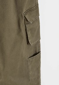 Oliwkowe spodnie cargo wykonane z bawełny; posiadają kieszenie boczne i miękką, teksturowaną tkaninę; standardowy krój z prostymi nogawkami.