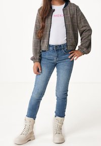 Kostkovaná bomber bunda v hnědé, růžové a navy; bílá tričko s nápisem "MEXX"; modré skinny džíny; béžové šněrovací boty.