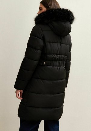 Manteau en duvet noir avec capuche en fausse fourrure, design matelassé, taille ceinturée et manches longues ; texture douce et coupe longueur genoux.