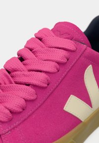 Pink suede sneaker with textured laces, contrasting beige logo, and gum rubber outsole. Features a padded collar for comfort.