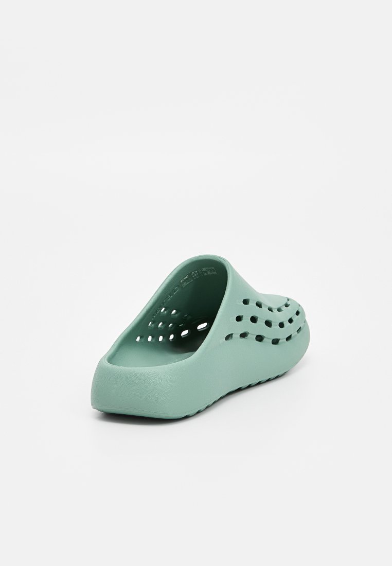 Jasnozielone klapki slip-on wykonane z teksturowanego materiału, z otworami wentylacyjnymi i delikatnie wyprofilowanym kształtem dla wygody.