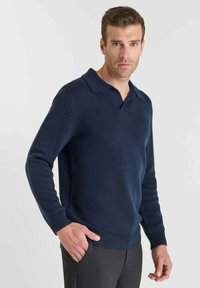 Jersey de punto azul marino con cuello plano, mangas largas, puños acanalados y dobladillo. Textura suave, ajuste casual, sin patrones ni acentos visibles.