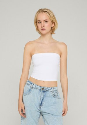 Top corto bianco senza spalline realizzato in materiale elasticizzato, con una texture liscia e scollatura dritta, abbinato a jeans in denim azzurro chiaro.